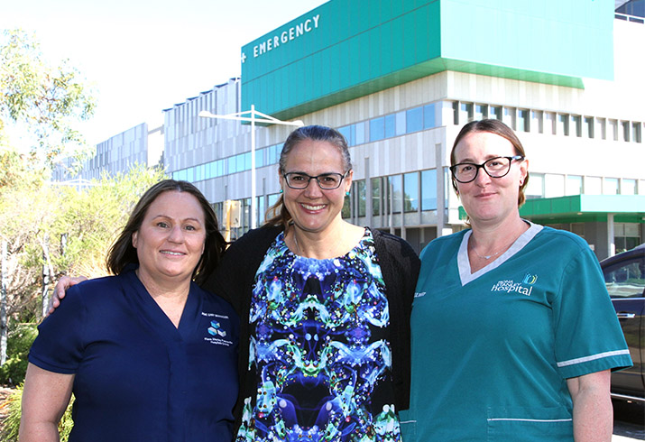 Three women stand in front of the Fiona Stanley Hospital Emergency Department