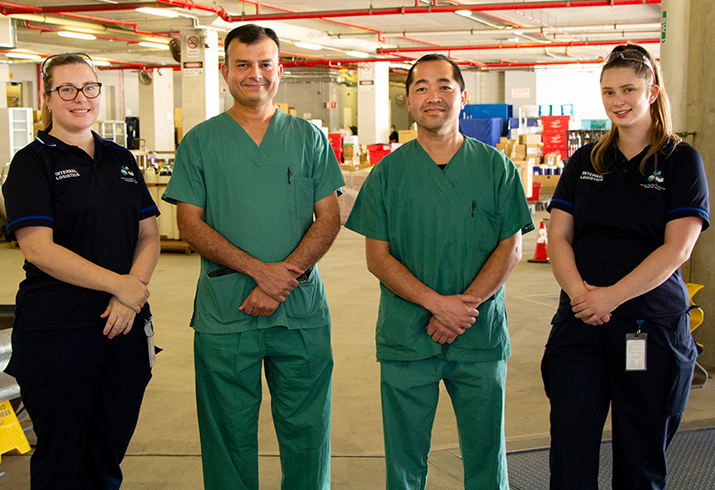Two women and two men stand side by side smiling in their hospital uniforms