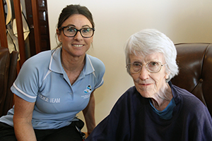 A female therapist sites beside and elderly woman