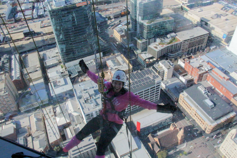 Woman abseiling with view of of city buildings in background