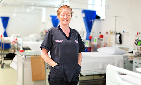 A smiling nurse stands in a treatment area.