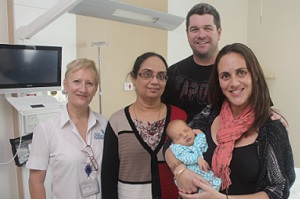 A woman holding a newborn baby with a man and two women standing beside her