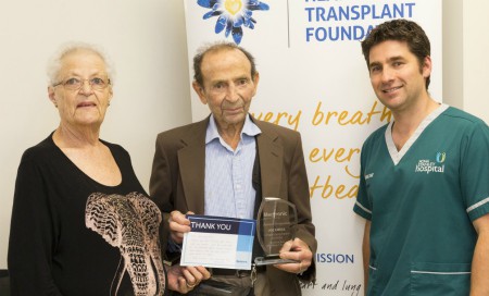 Man and woman hold award standing next to Fiona Stanley Hospital clinician