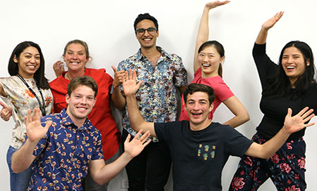Group of staff in colourful shirts with their hands in the air