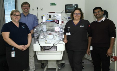 Neonatal staff standing around incubator machine