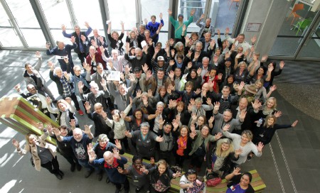 Group of people standing in hospital concourse with their arms in the air