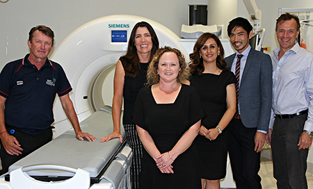Three men and three women standing beside some medical imaging equipment