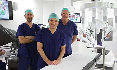 Three men in surgical scrubs standing in an operating theatre